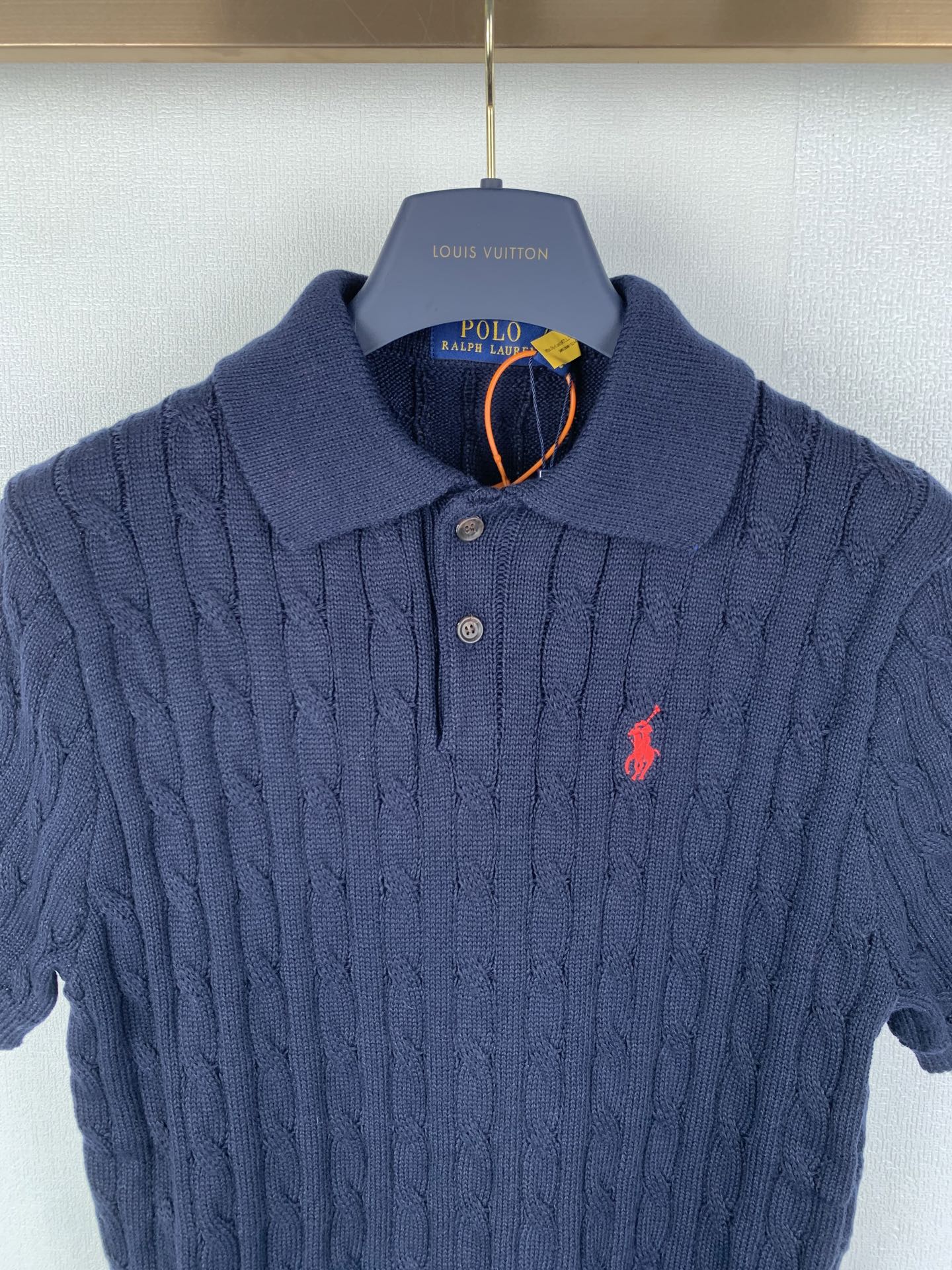 Dark navy cable-knit polo shirt with button placket, red logo, ribbed collar