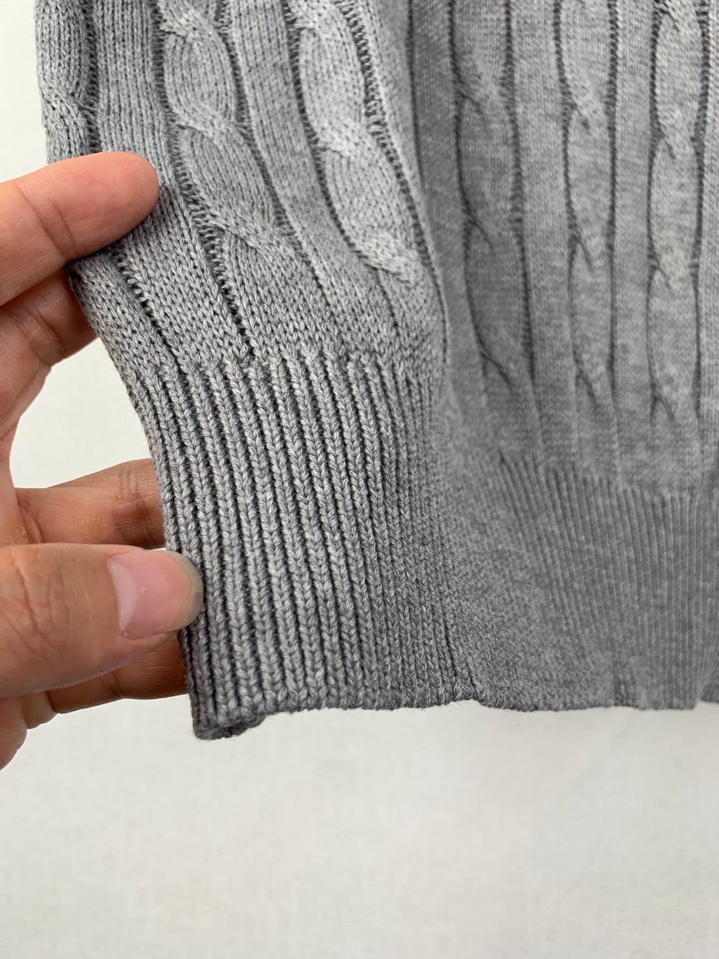 Gray knit polo shirt hem with ribbed bottom band and cable pattern