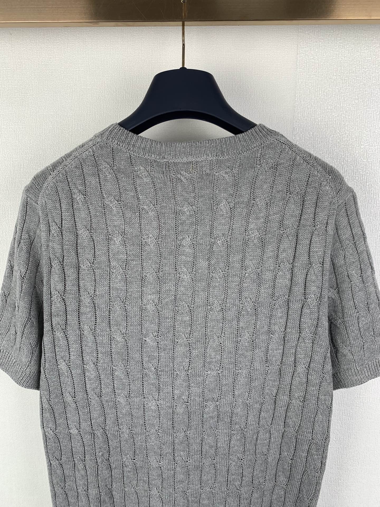 Gray knit polo shirt back close-up showing cable knit texture and ribbed neckline