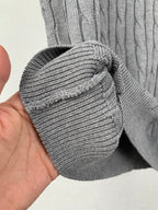 Gray knit sleeve cuff folded over, ribbed edge on cable-knit polo shirt