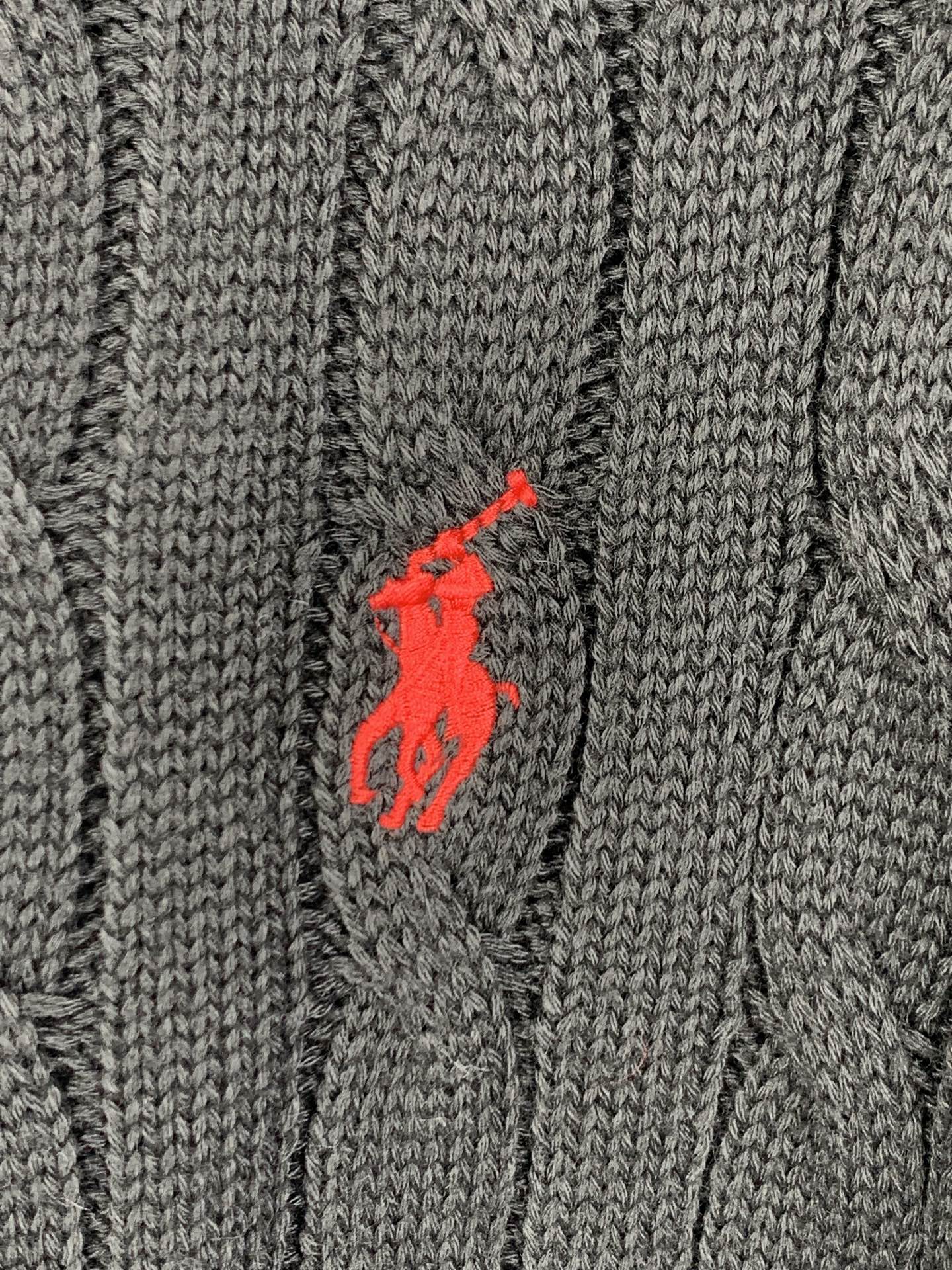 Red polo player logo on dark cable-knit sweater fabric