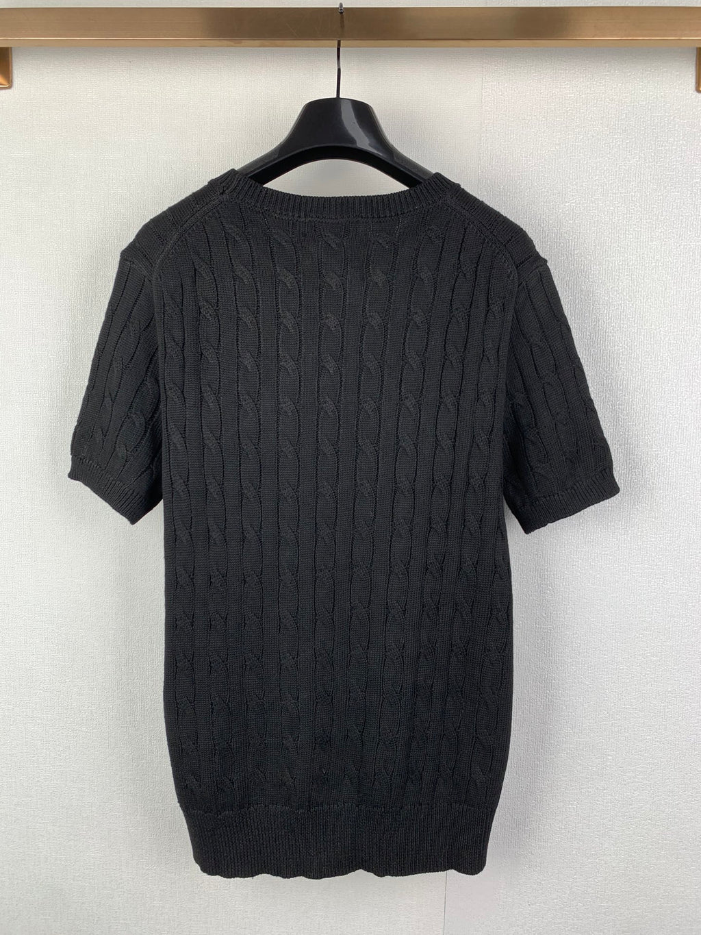 Cable-knit sweater back view in dark knit with short sleeves and ribbed hem