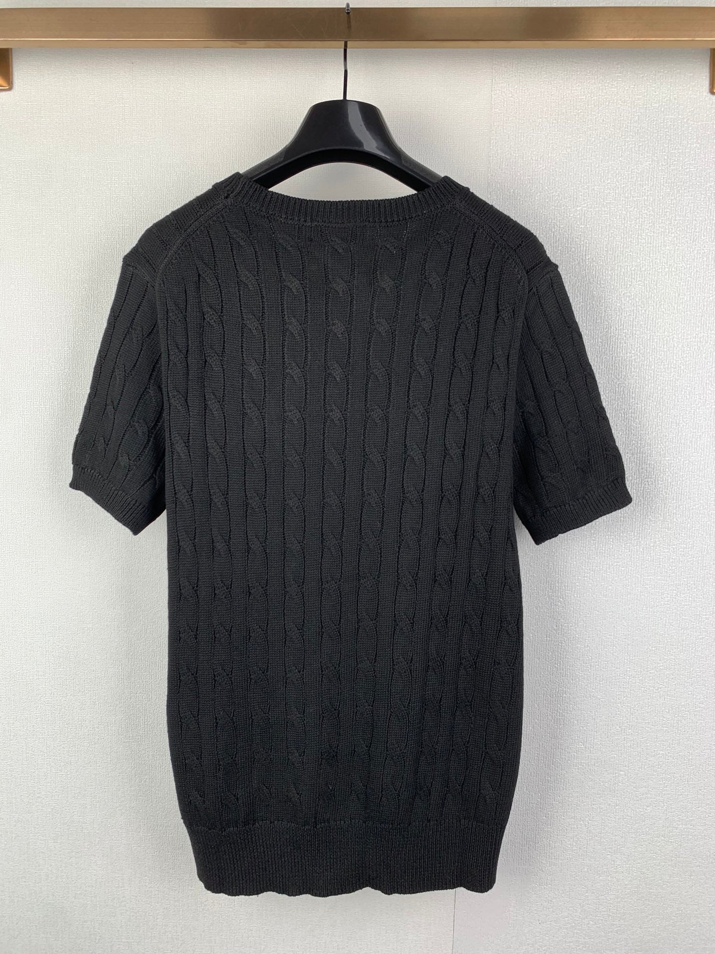 Cable-knit sweater back view in dark knit with short sleeves and ribbed hem