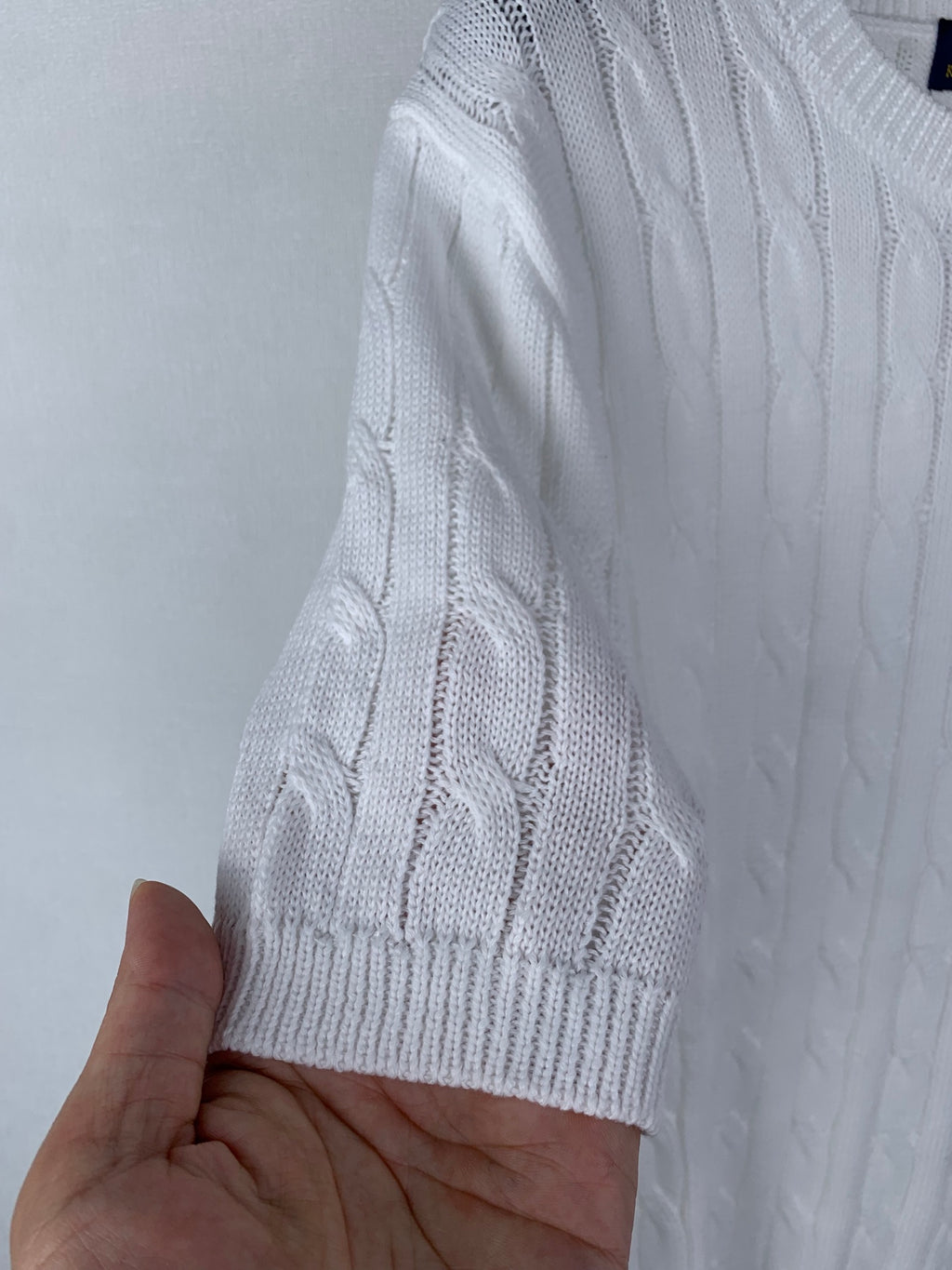 White knit sweater sleeve with ribbed cuff and cable texture