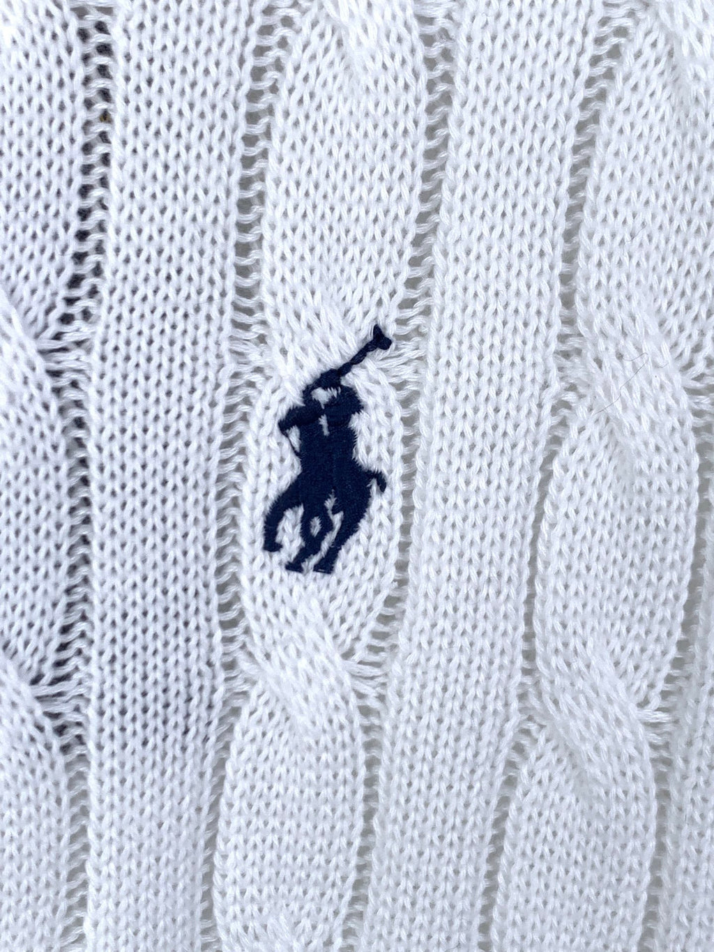 Small navy polo logo embroidered on white cable-knit sweater fabric