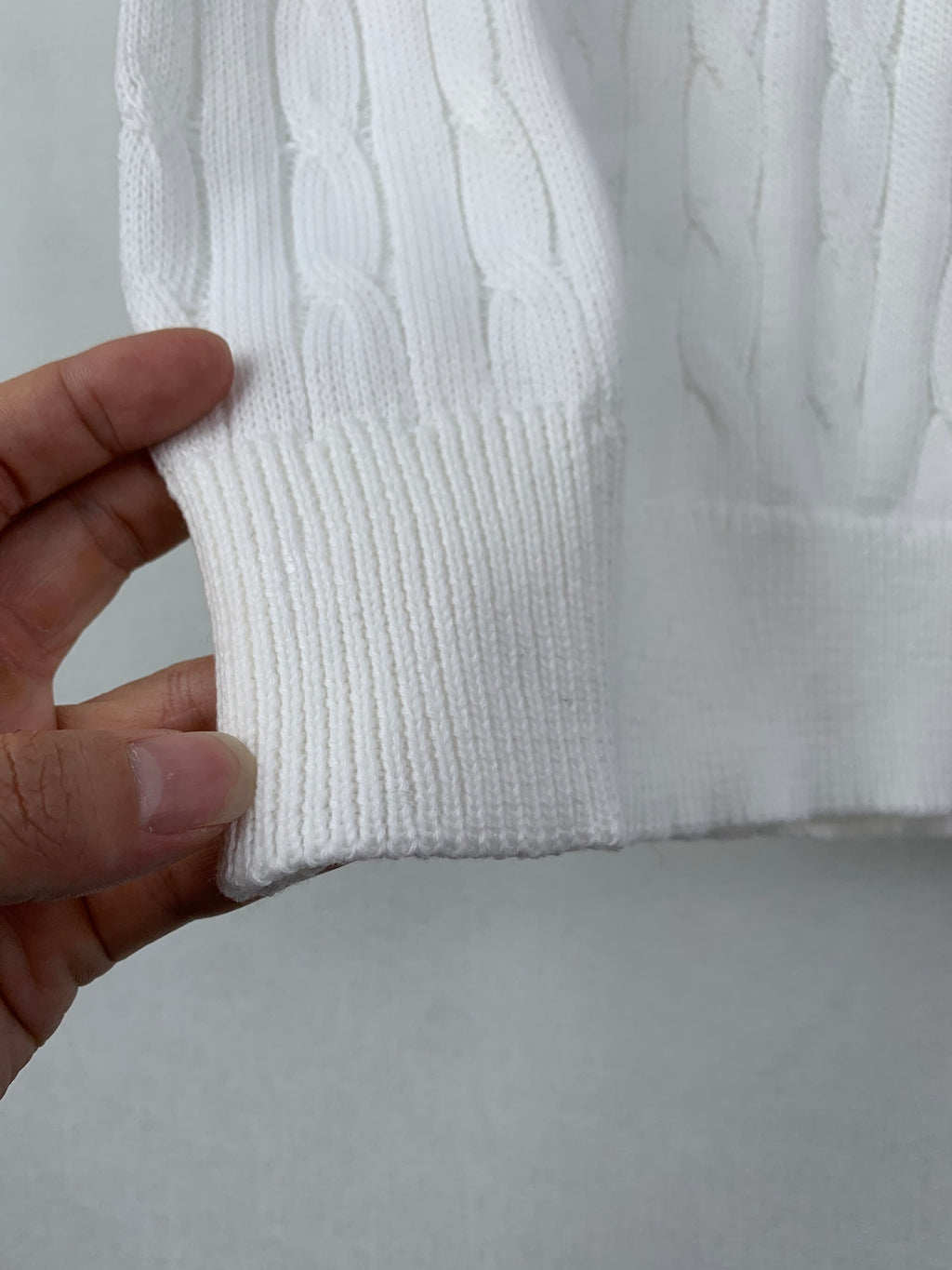 White cable-knit sweater hem with ribbed cuff detail