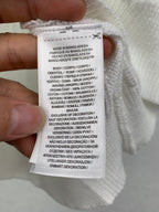 Inside garment label with size and care instructions on white knit sweater