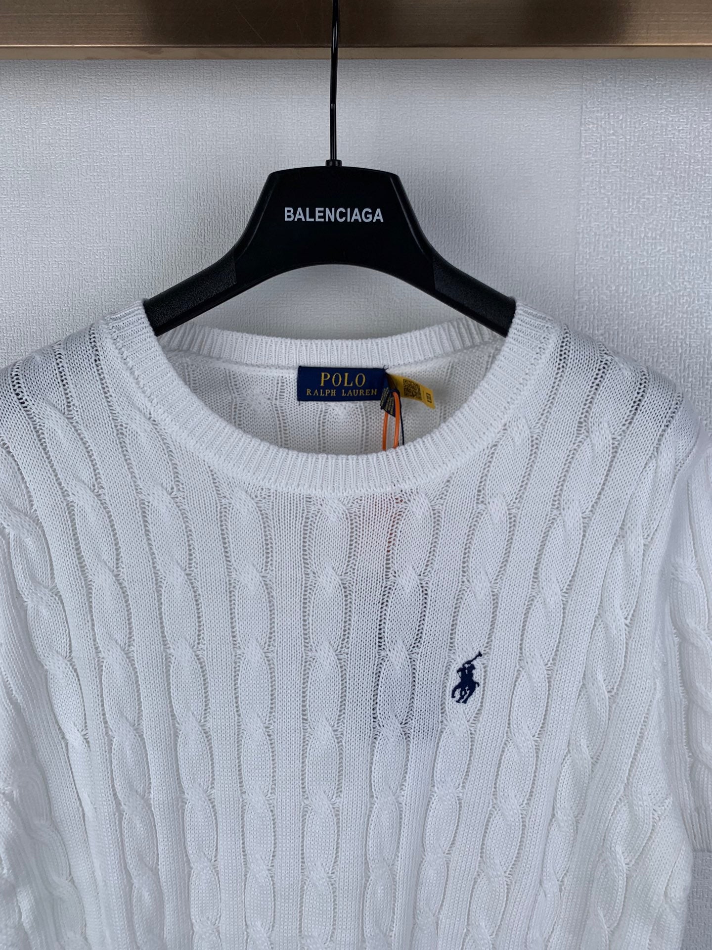 White cable-knit crewneck sweater with navy polo logo at left chest