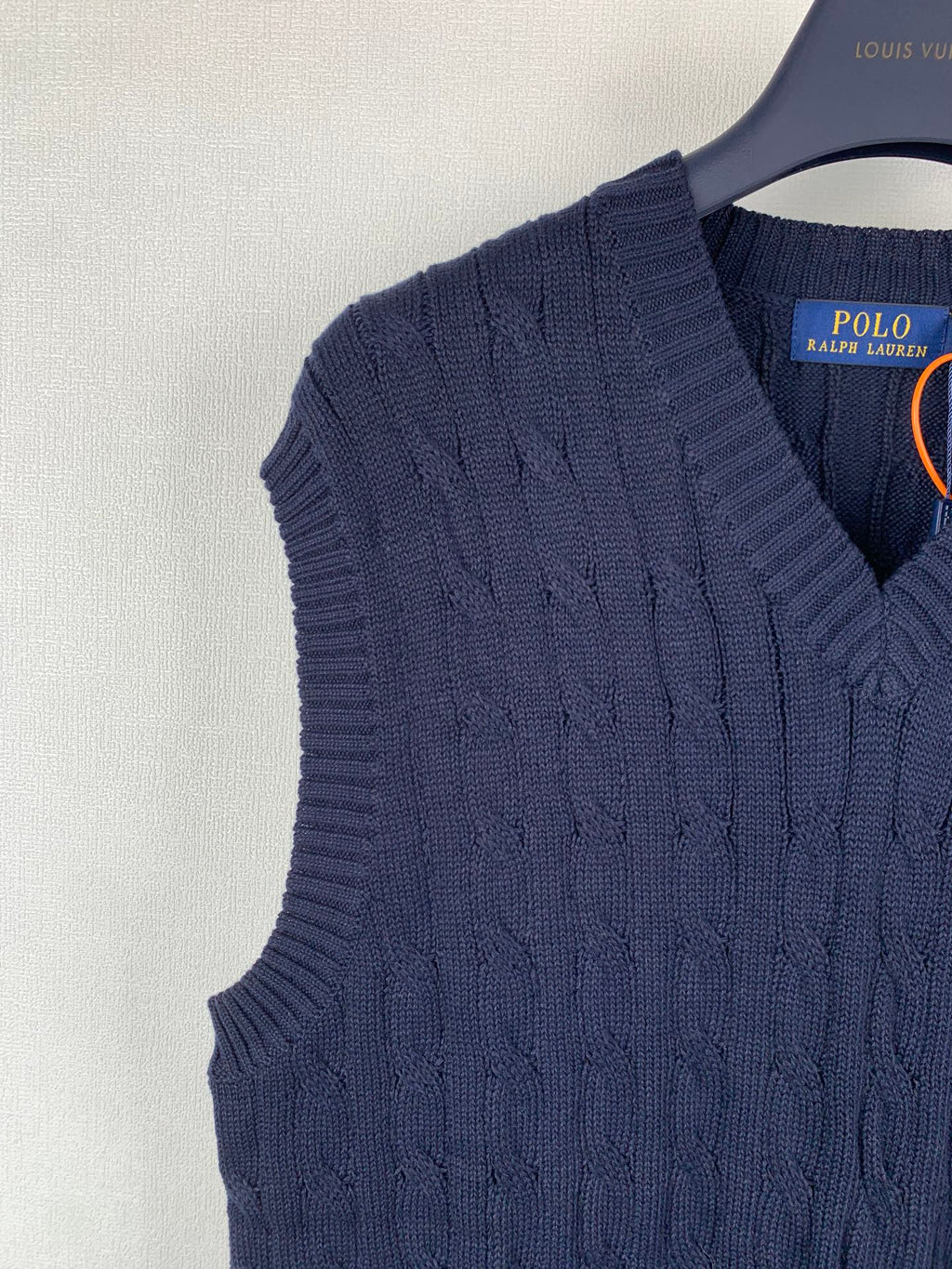 Navy cable-knit sweater vest shoulder with V-neck opening detail