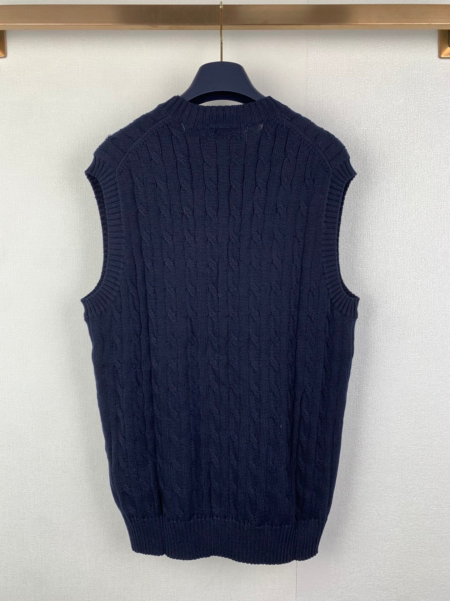 Back of navy cable-knit sweater vest on hanger