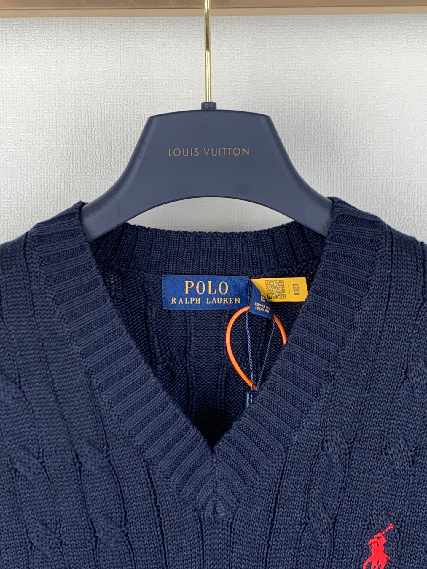 Navy cable-knit sweater vest with V-neck, red polo logo, and neck tag