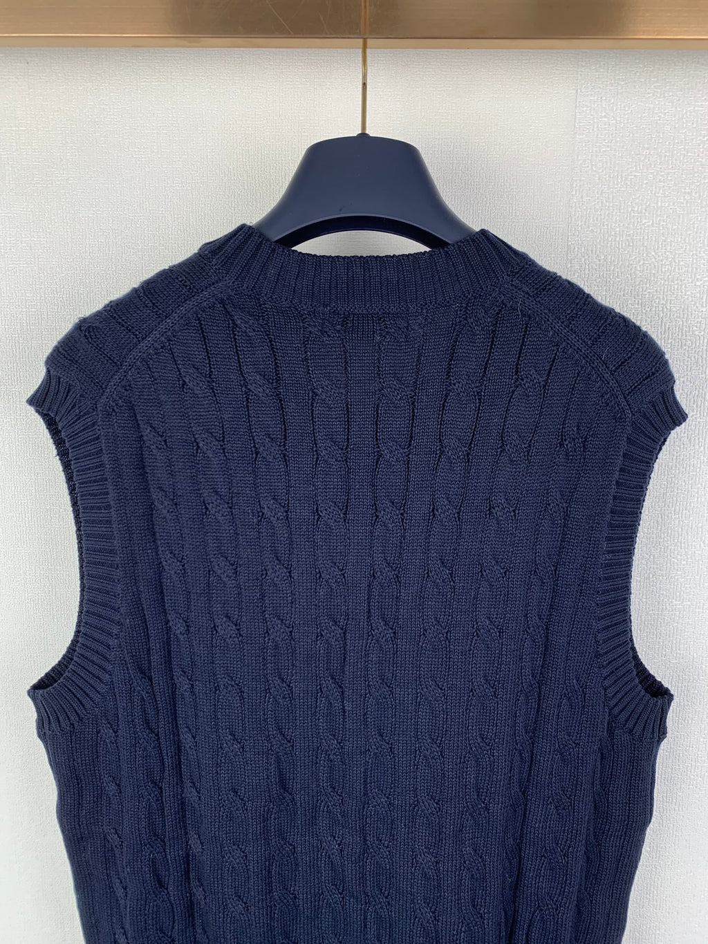 Navy cable-knit sweater vest with ribbed collar and textured shoulder pattern