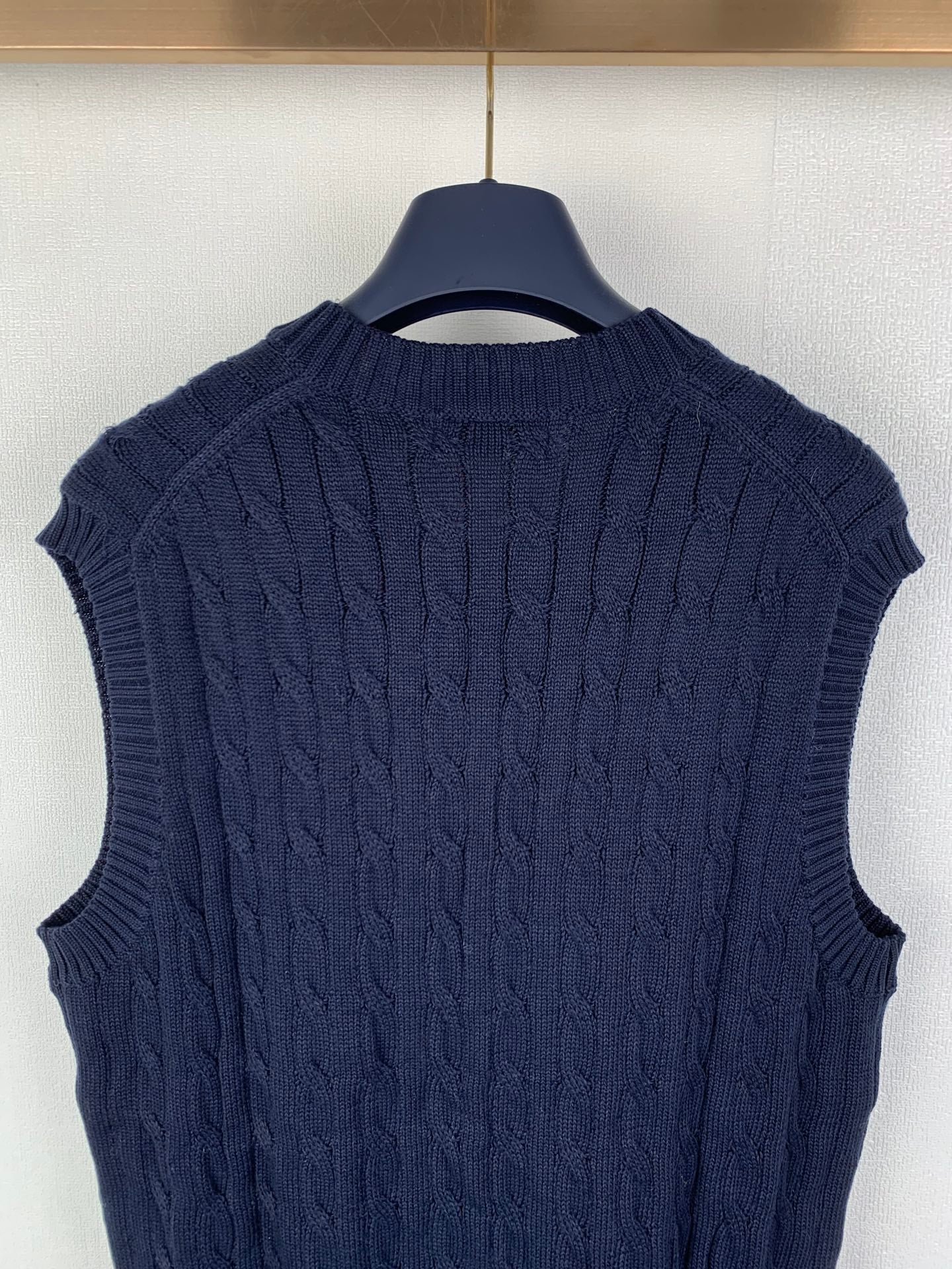 Navy cable-knit sweater vest with ribbed collar and textured shoulder pattern