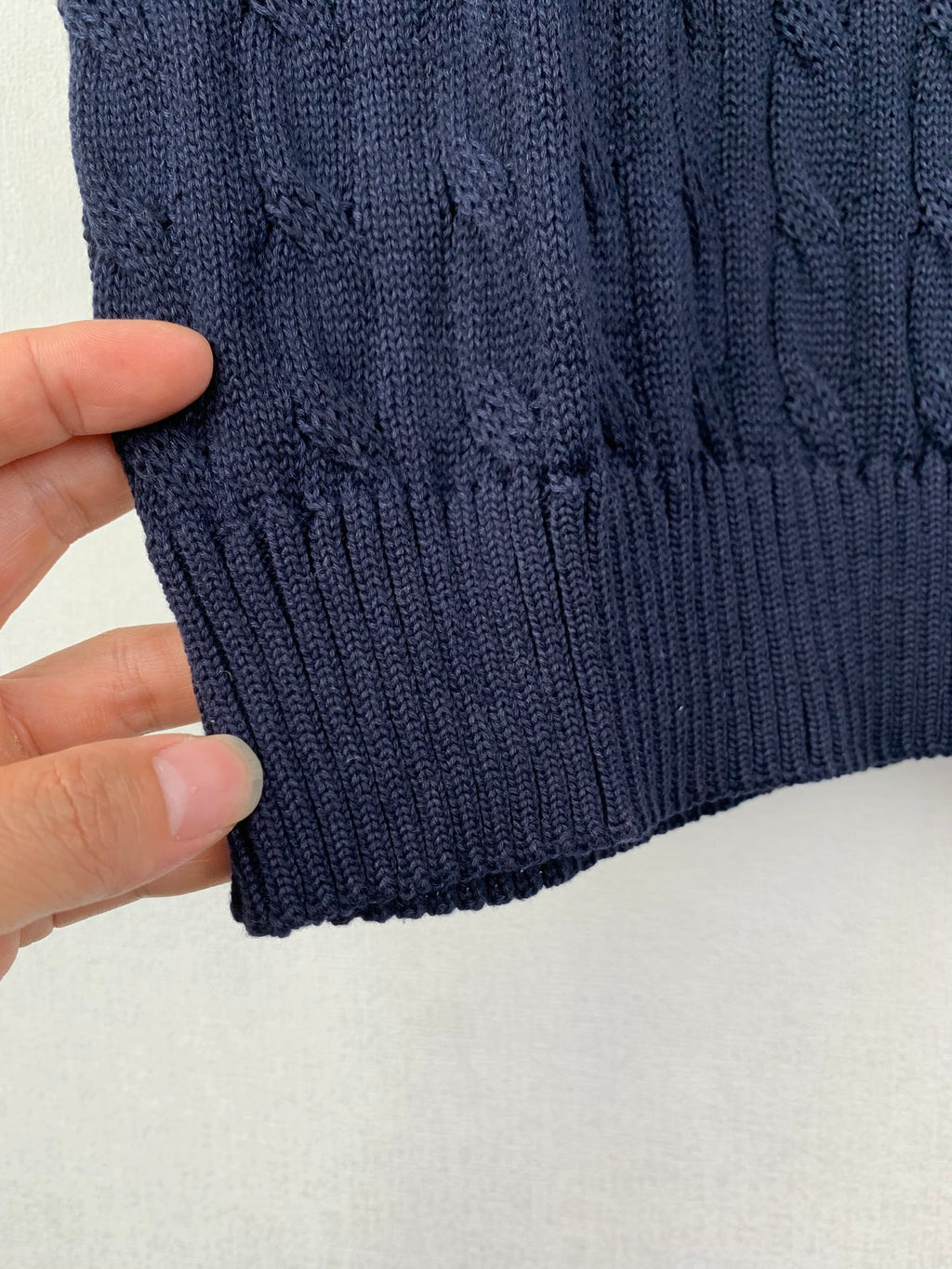 Navy ribbed knit hem on a cable-knit sweater vest