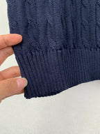 Navy ribbed knit hem on a cable-knit sweater vest