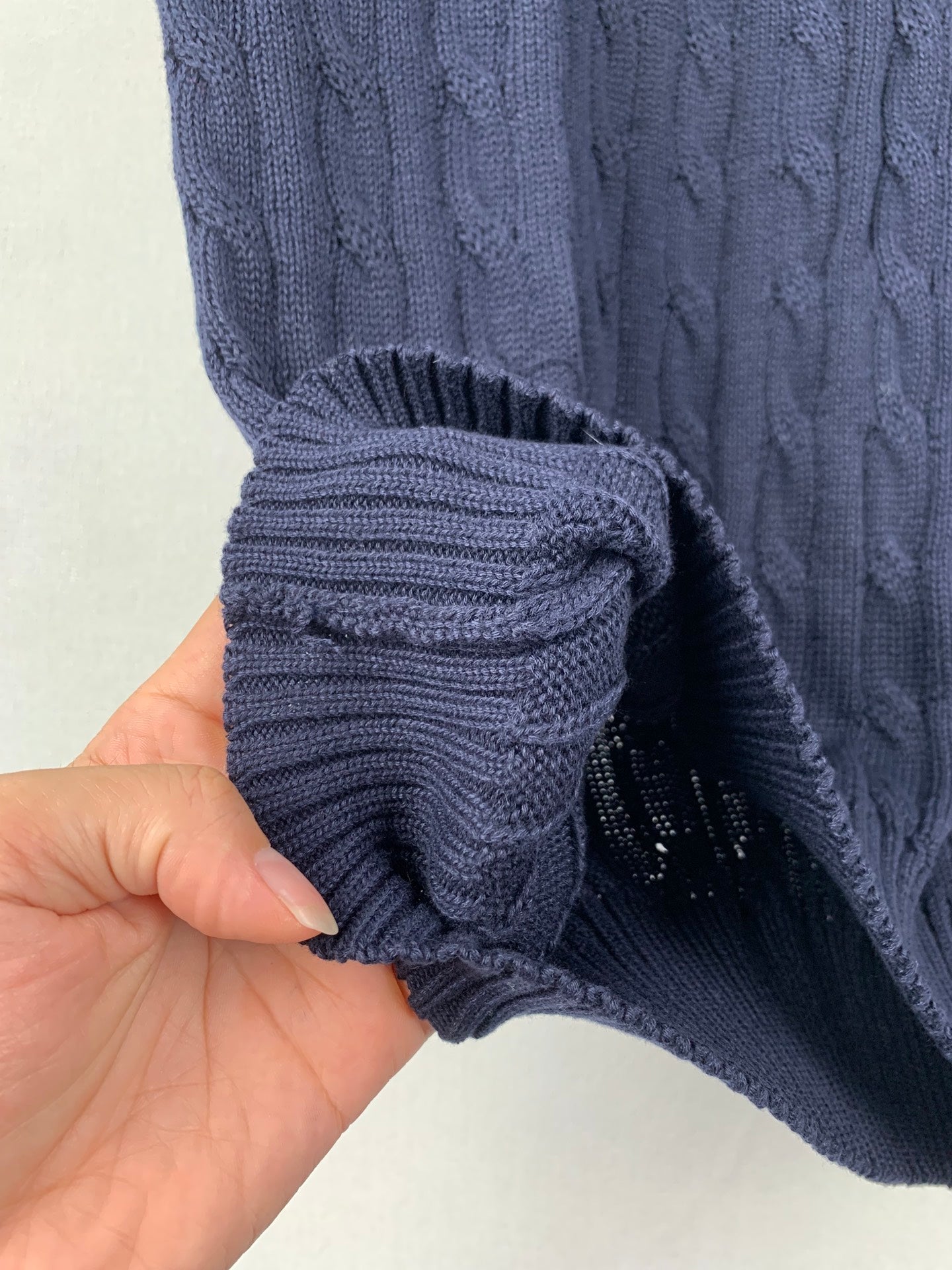 Navy cable-knit sweater vest hem fold and sleeve cuff detail