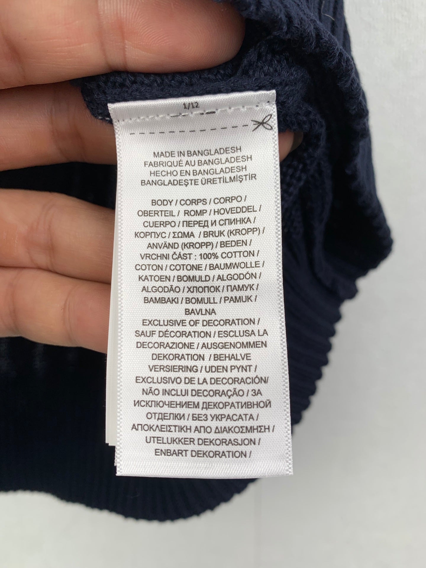 Inside size and care label on navy sweater vest