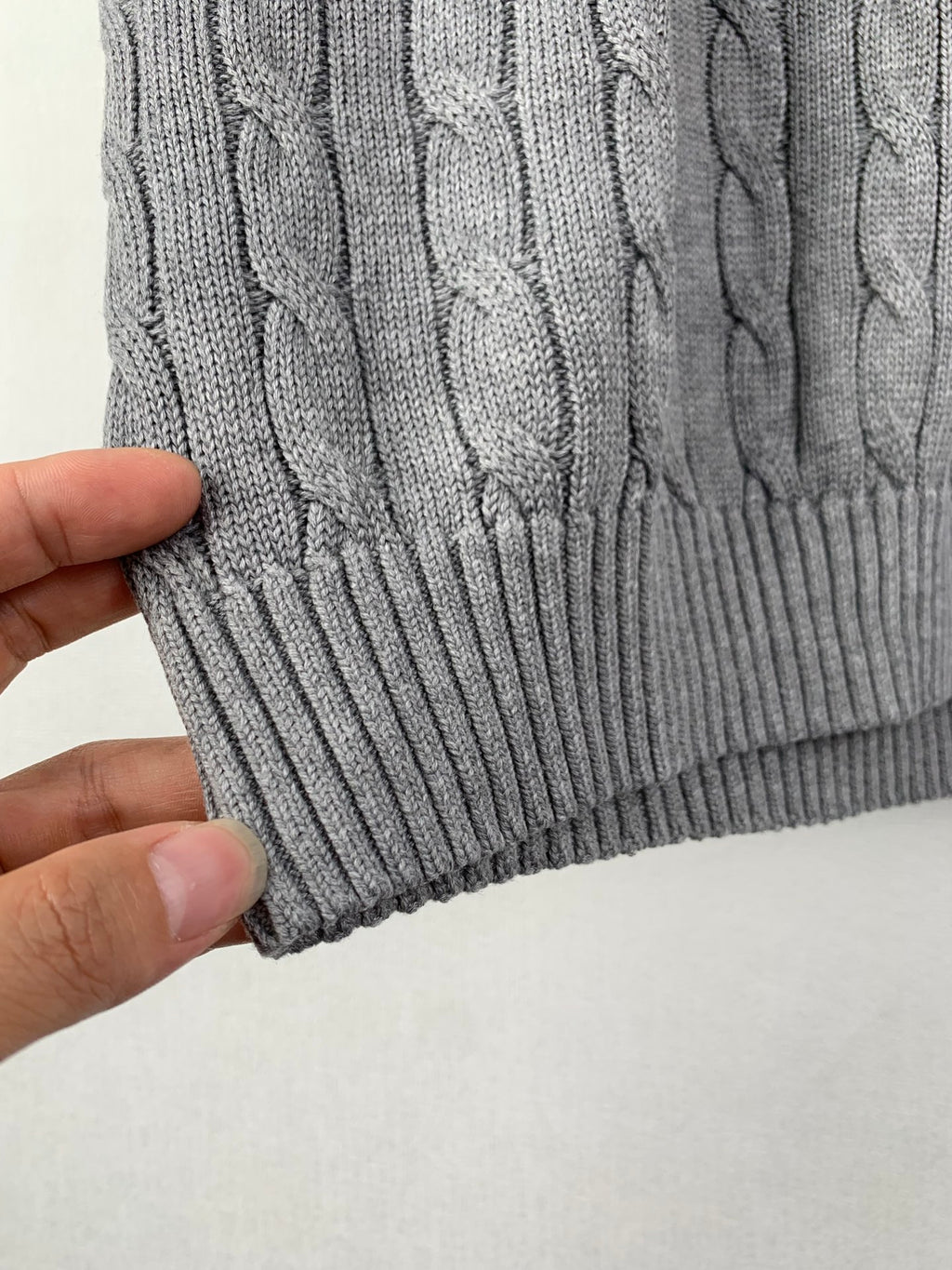 Gray ribbed knit hem with cable-knit texture on sleeveless sweater vest