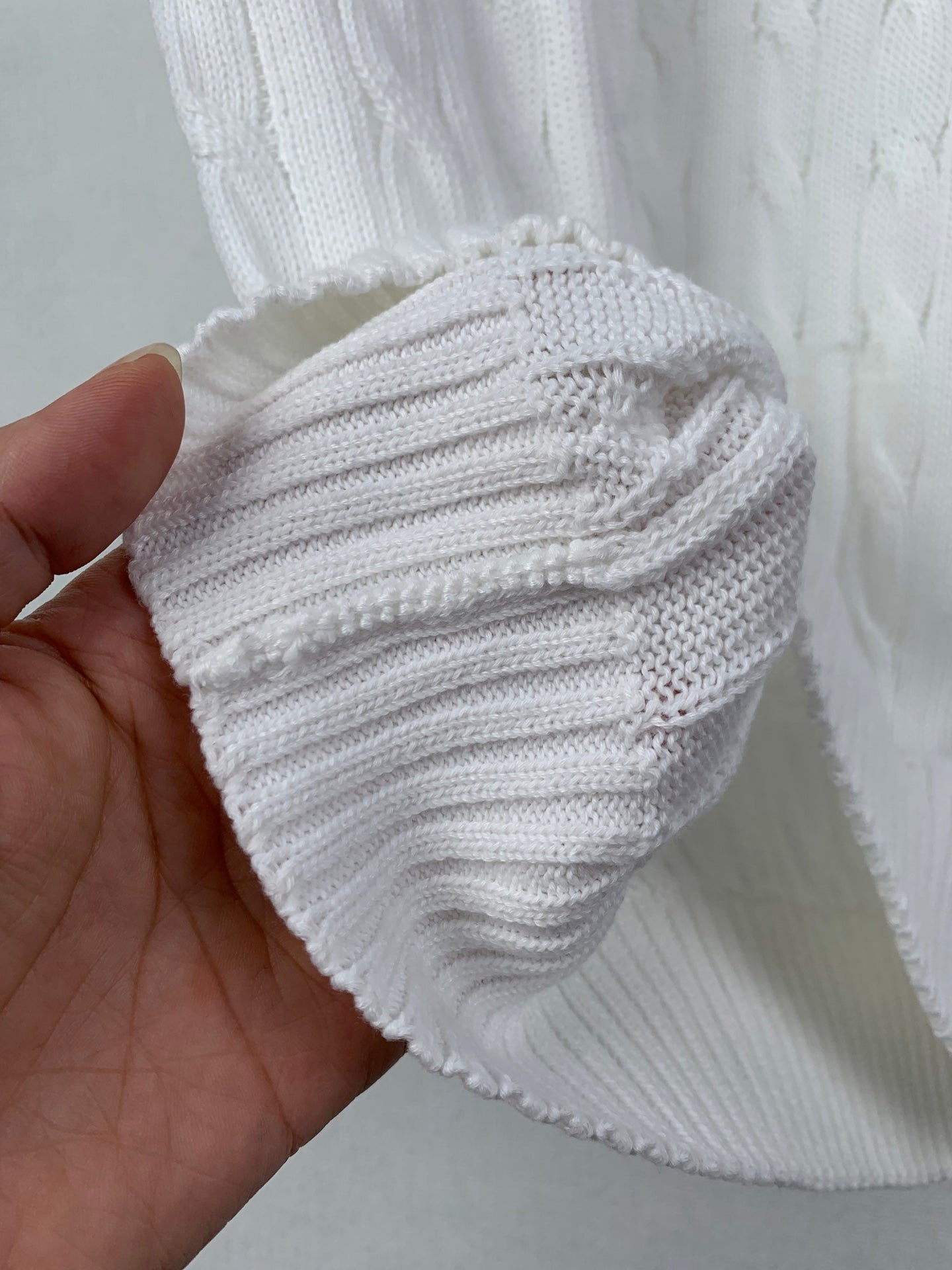 Folded white knit sweater vest with cable-stitch texture
