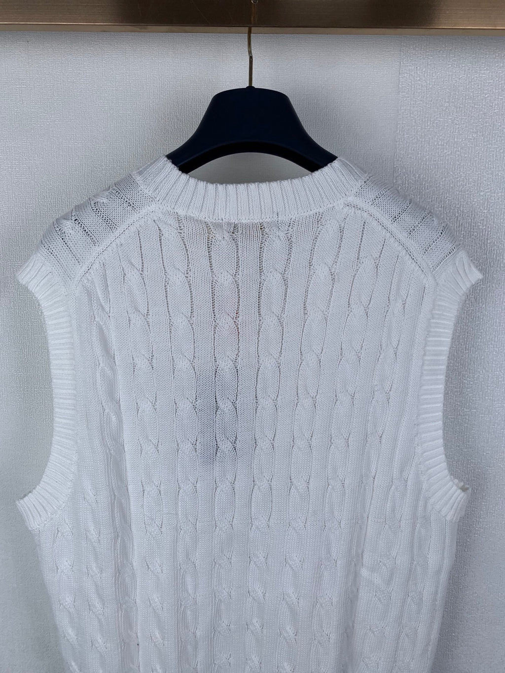 White sleeveless cable-knit sweater vest showing knit texture on back