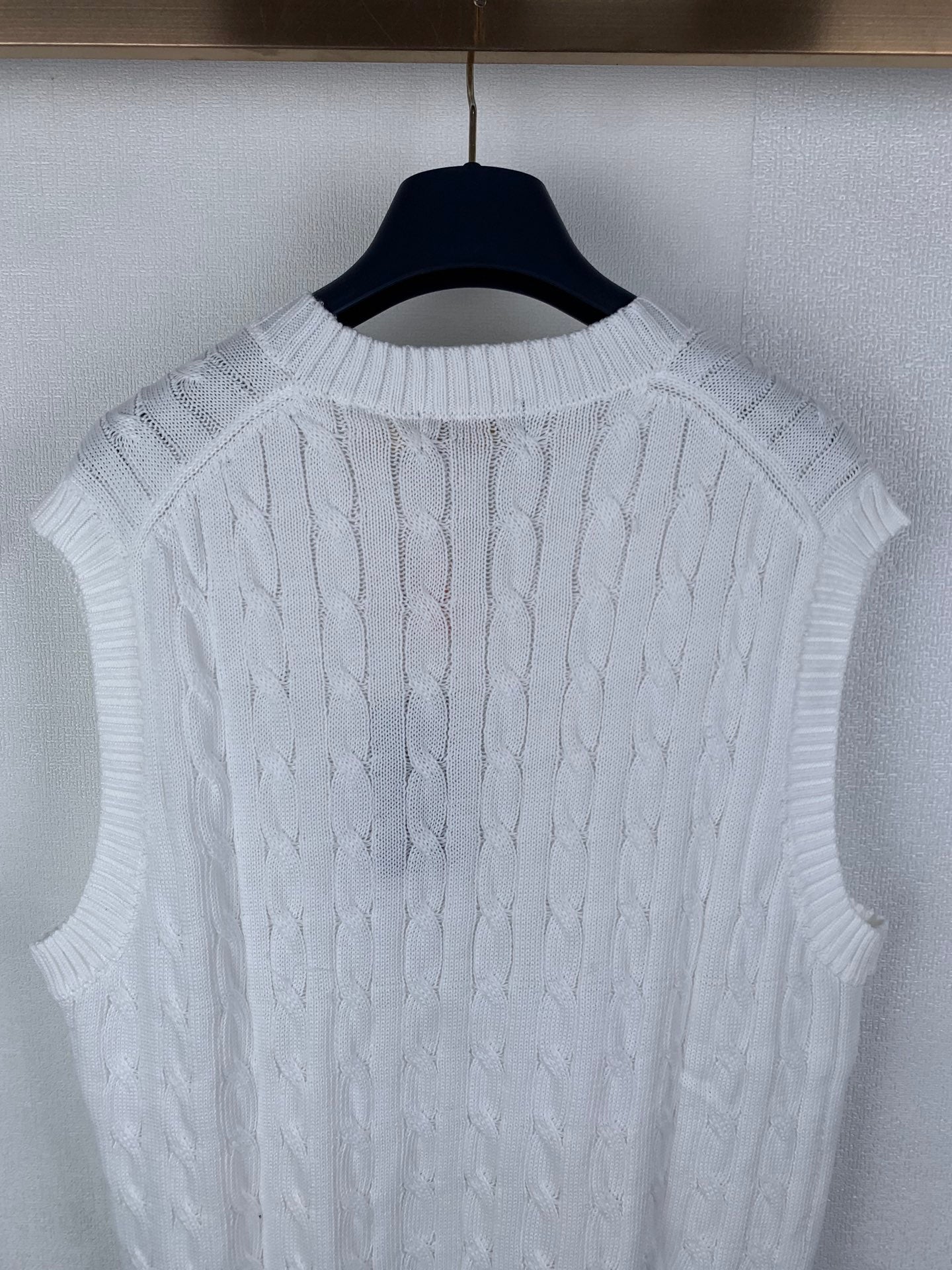 White sleeveless cable-knit sweater vest showing knit texture on back