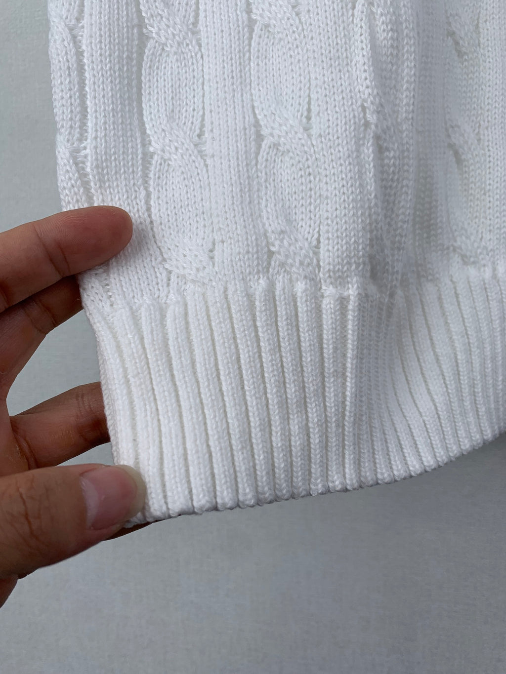 White knit sweater vest hem with ribbed cuff and vertical cable pattern