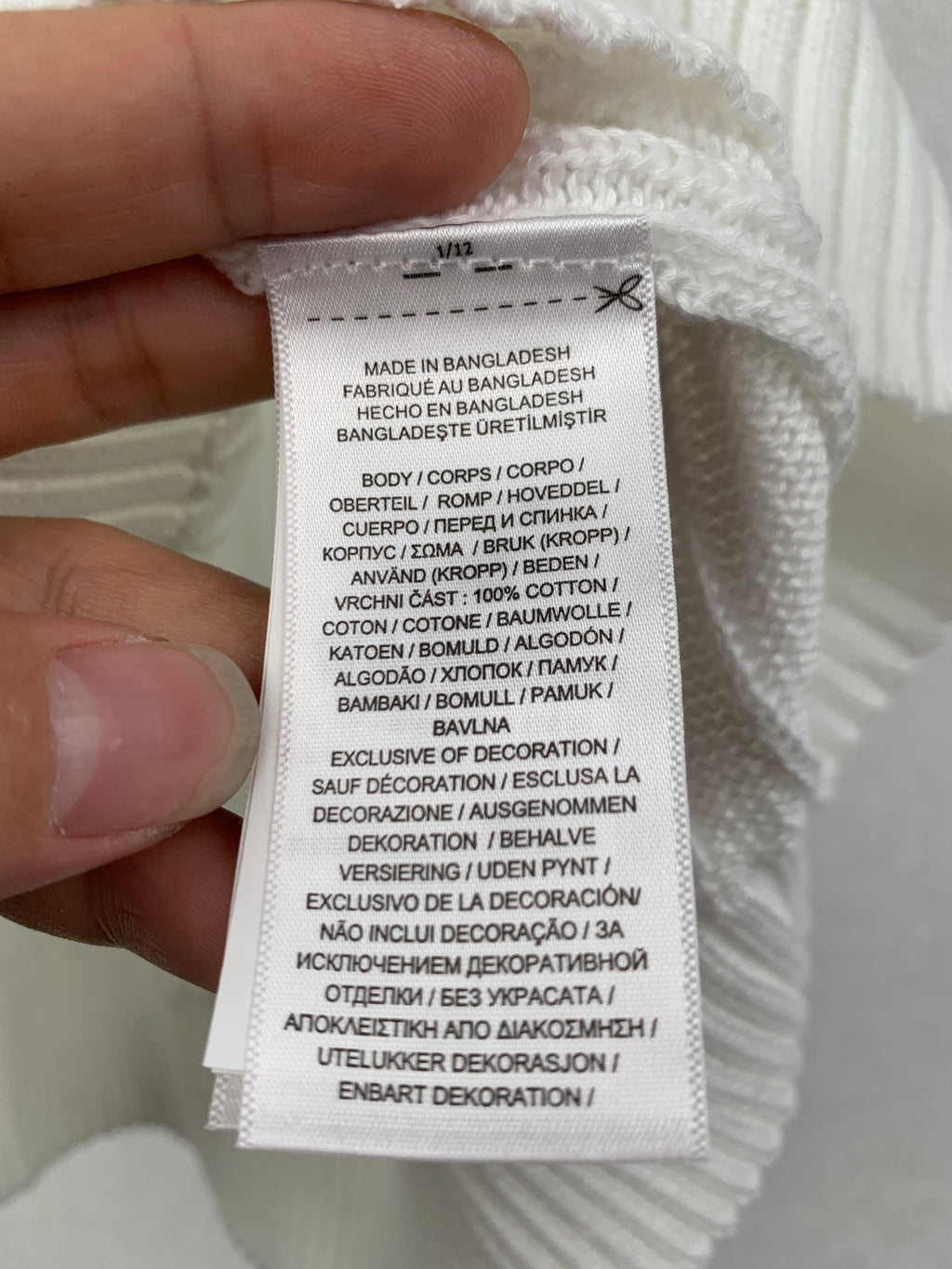 Clothing care label on white knit sweater vest, made in Bangladesh