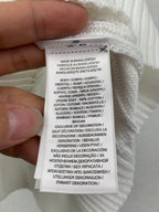 Clothing care label on white knit sweater vest, made in Bangladesh
