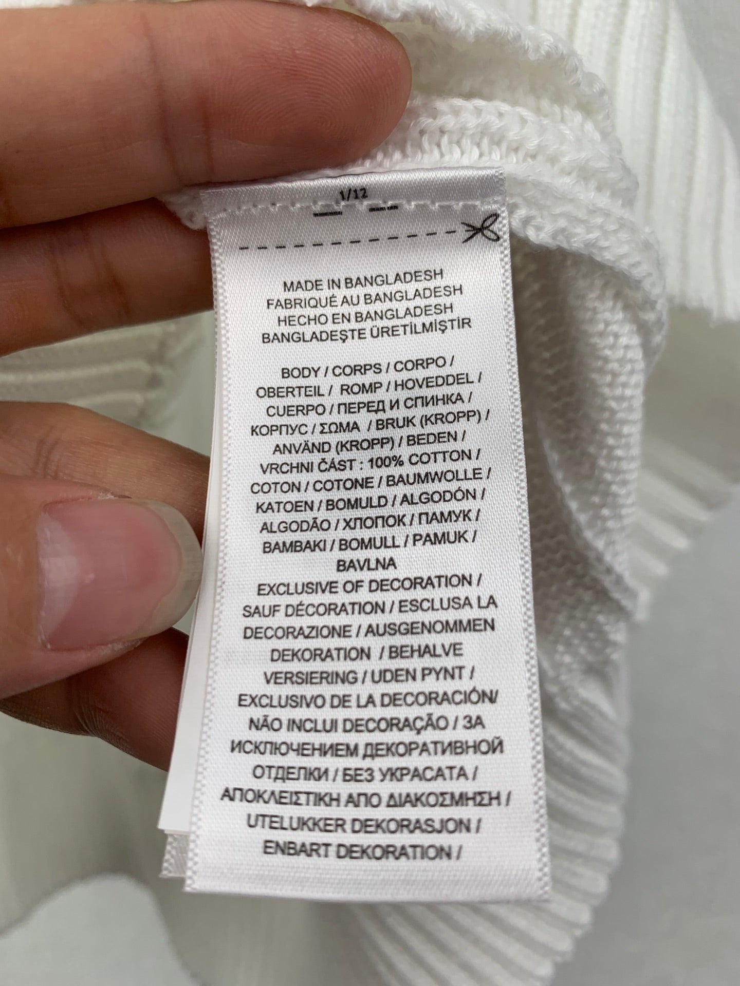 Clothing care label on white knit sweater vest, made in Bangladesh