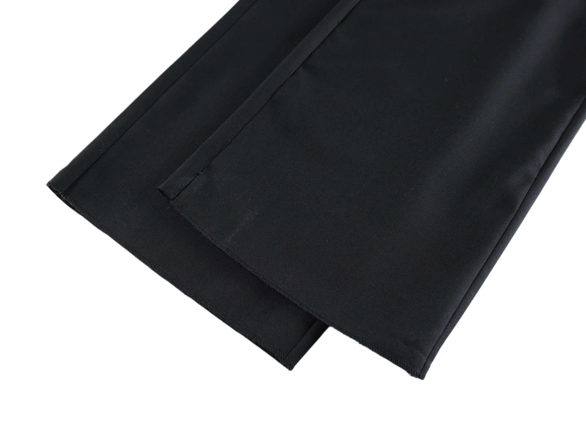 Black pants leg with visible inner seam and folded hem