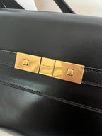 Black YSL handbag front flap with rectangular gold-tone lock plates