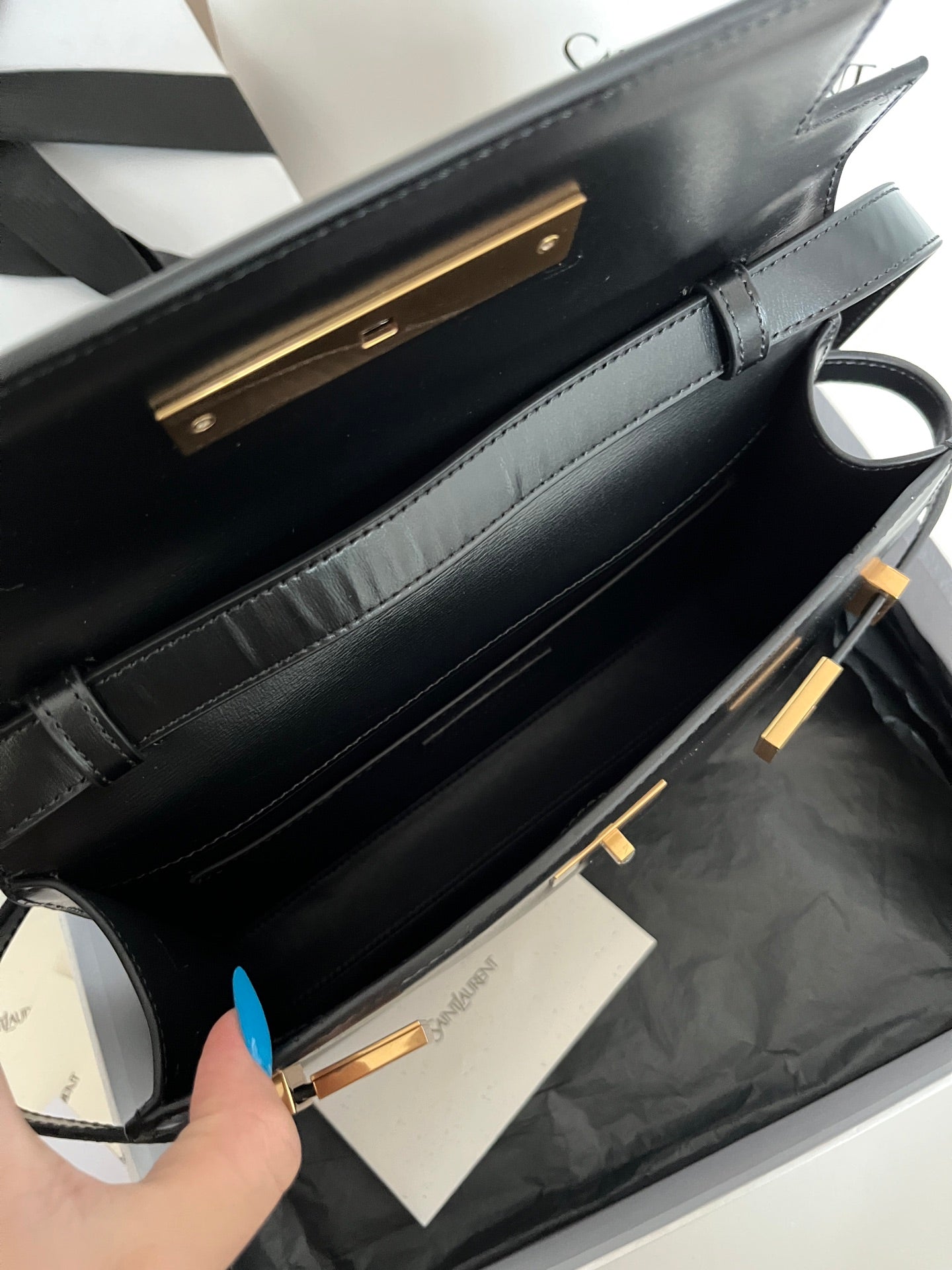 Black YSL handbag interior shown with gold-tone hinges and strap rings