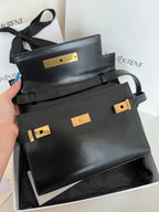 Black YSL handbag with gold-tone front panel, flap and curved handles
