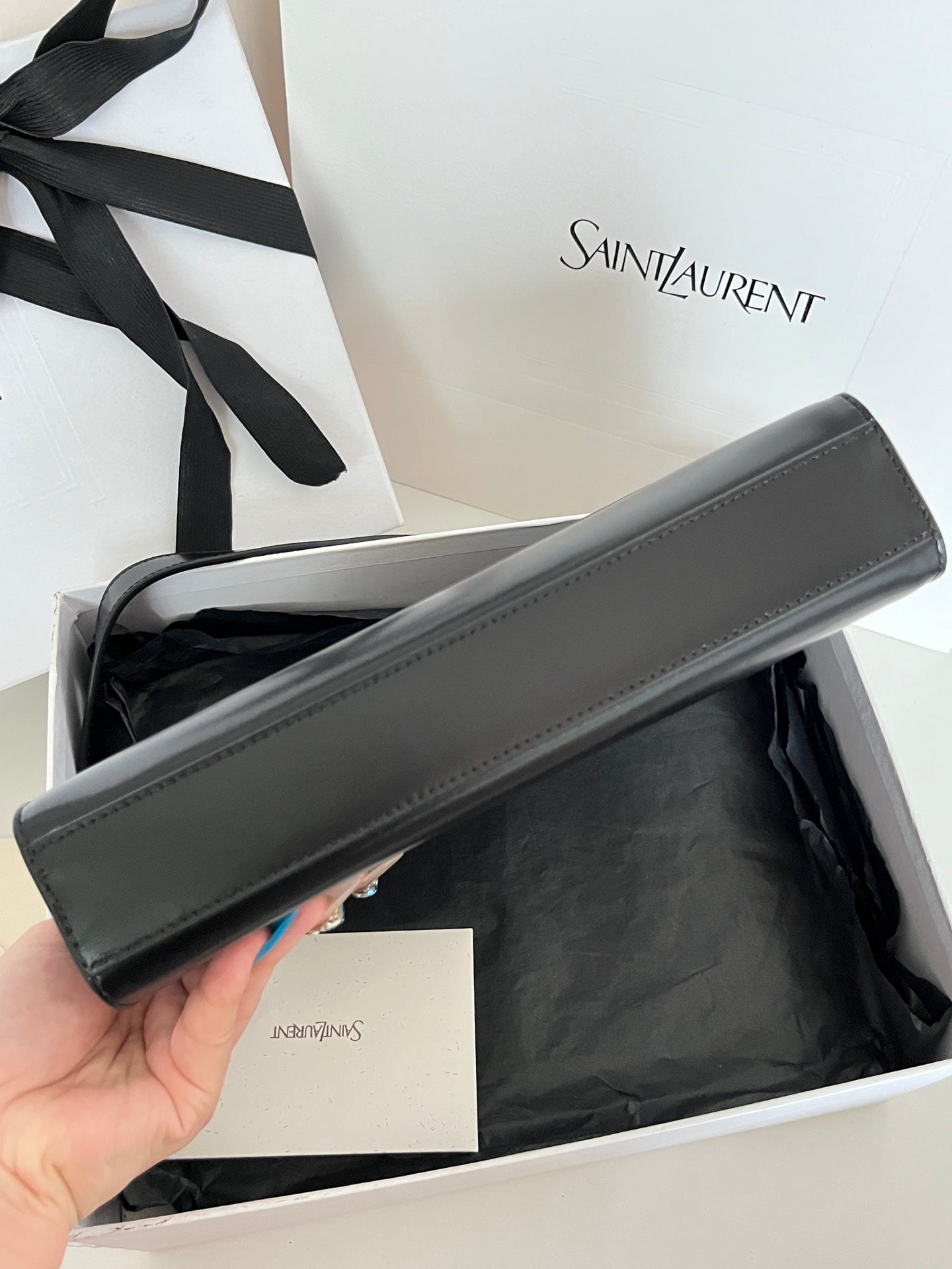 Long black YSL handbag detail view with stitched trim and strap