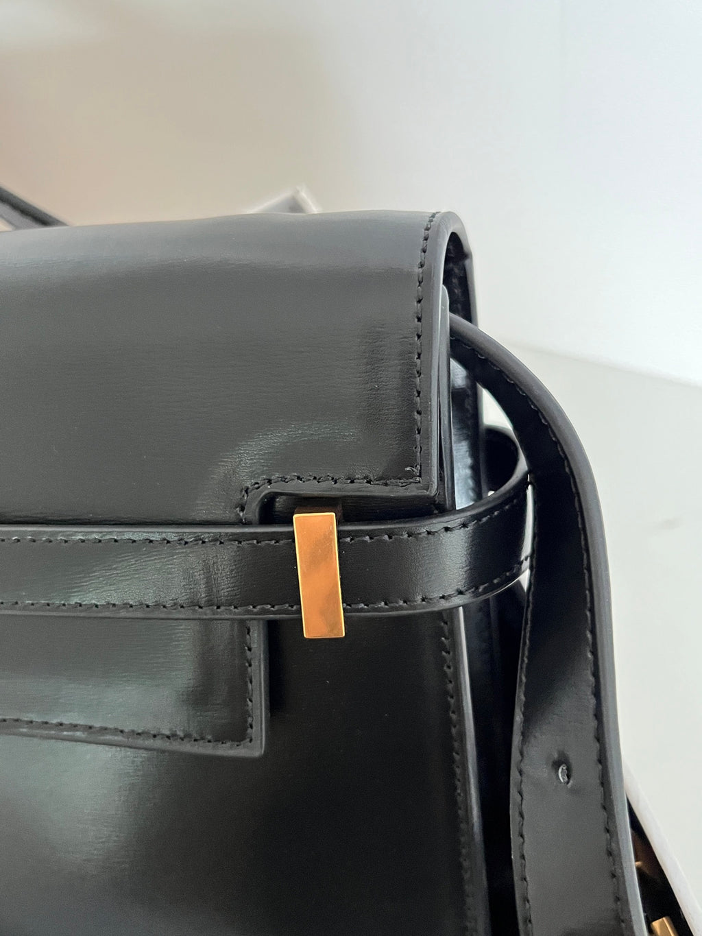 Black YSL handbag corner with gold-tone bar accent and top strap