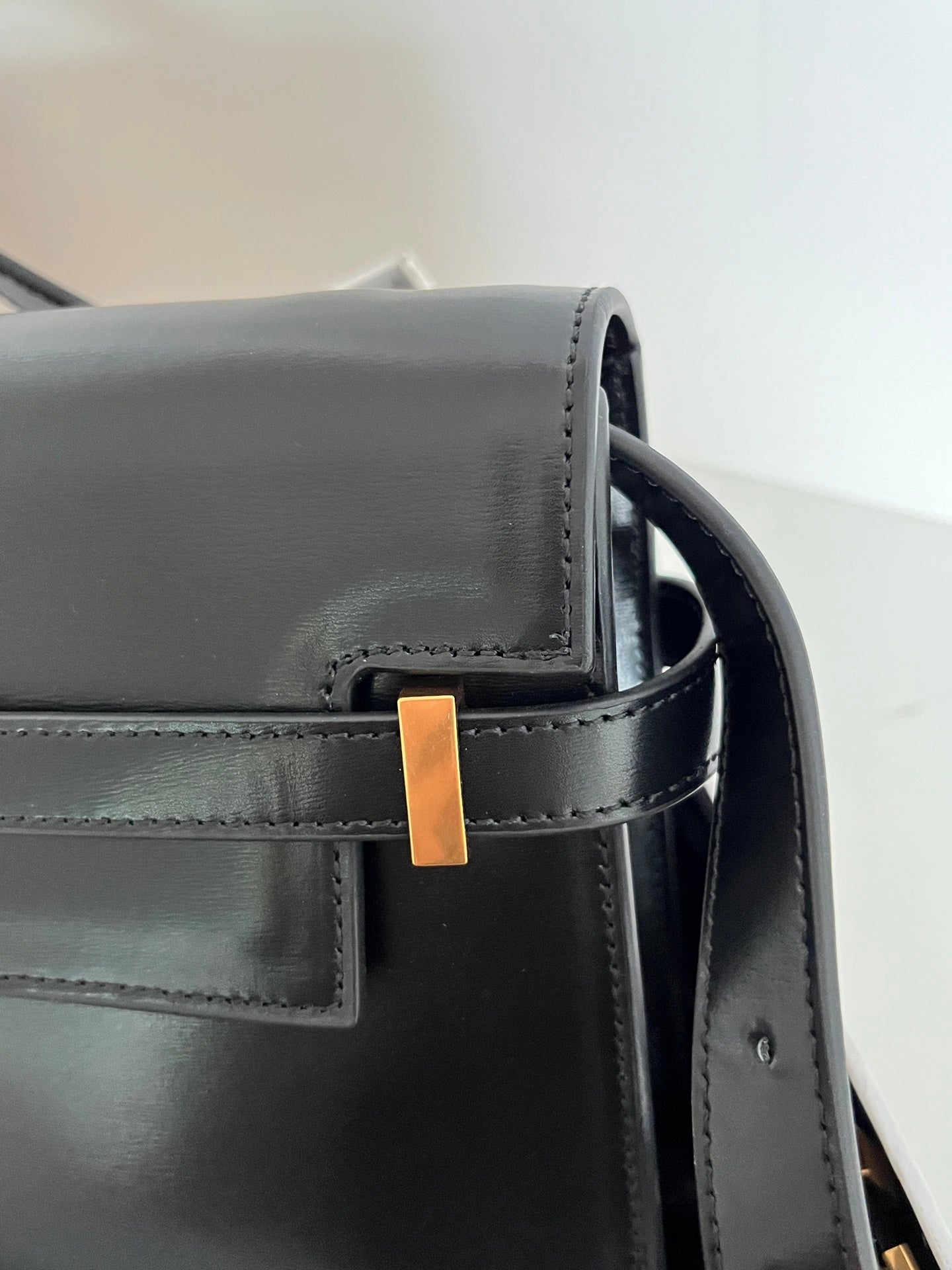 Black YSL handbag corner with gold-tone bar accent and top strap