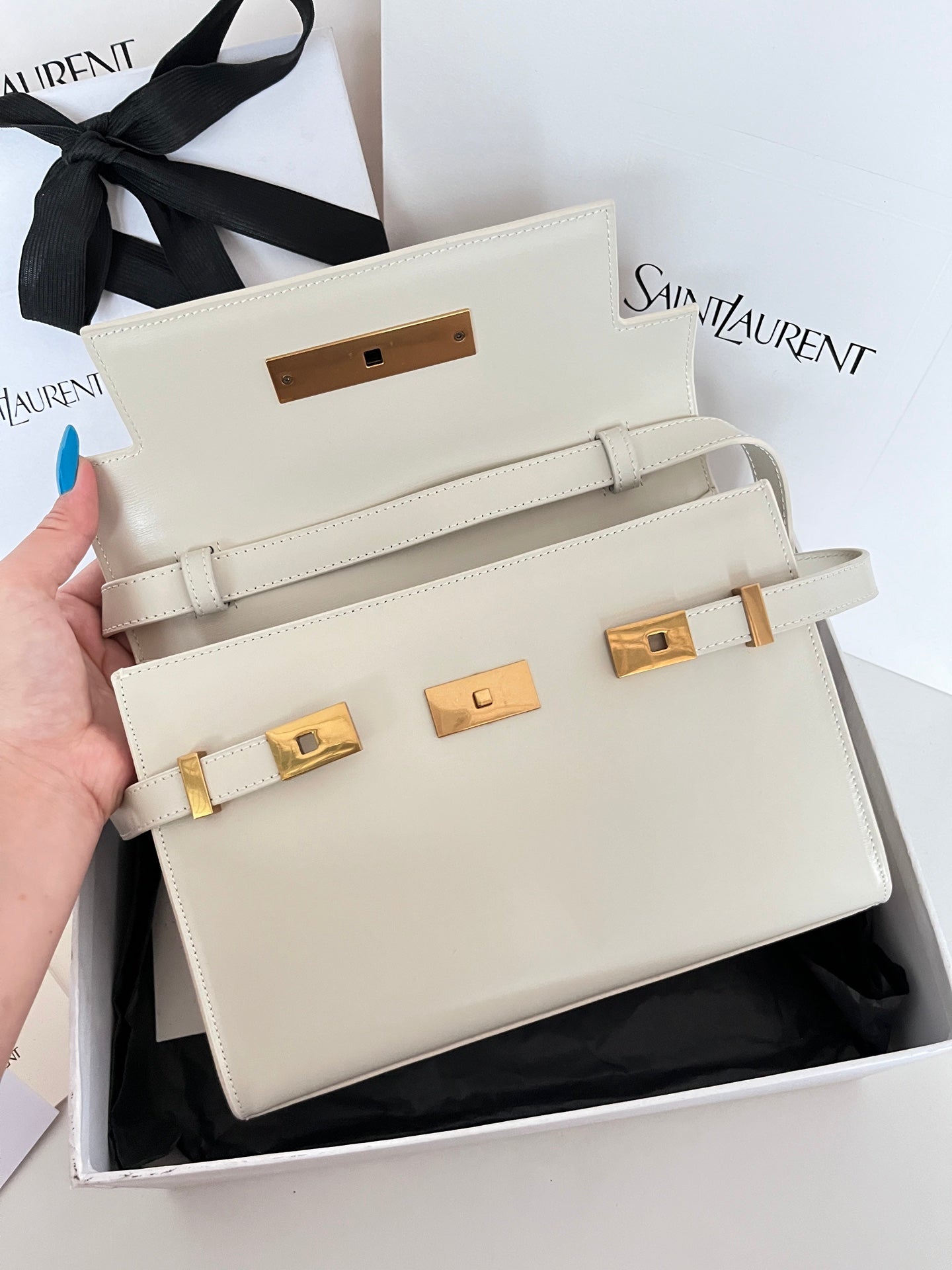 Cream leather handbag front with gold-tone belt hardware and top handle straps