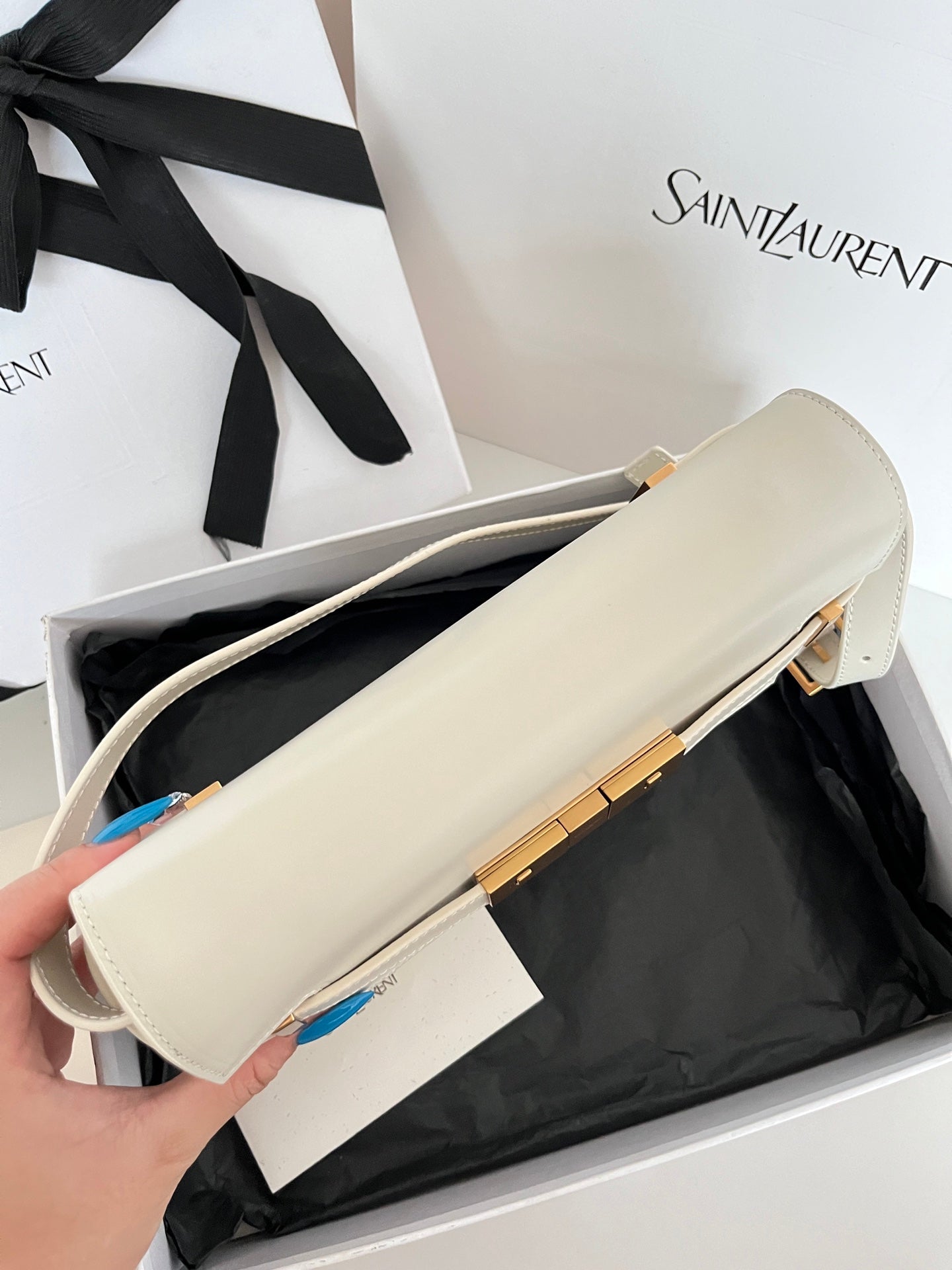 Cream leather handbag with gold-tone hardware, side profile and shoulder strap