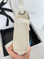 Cream leather handbag with top handle and gold clasp, held upright