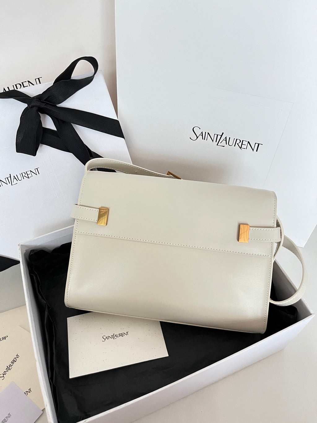 Cream leather handbag with gold clasp and curved shoulder strap, front view