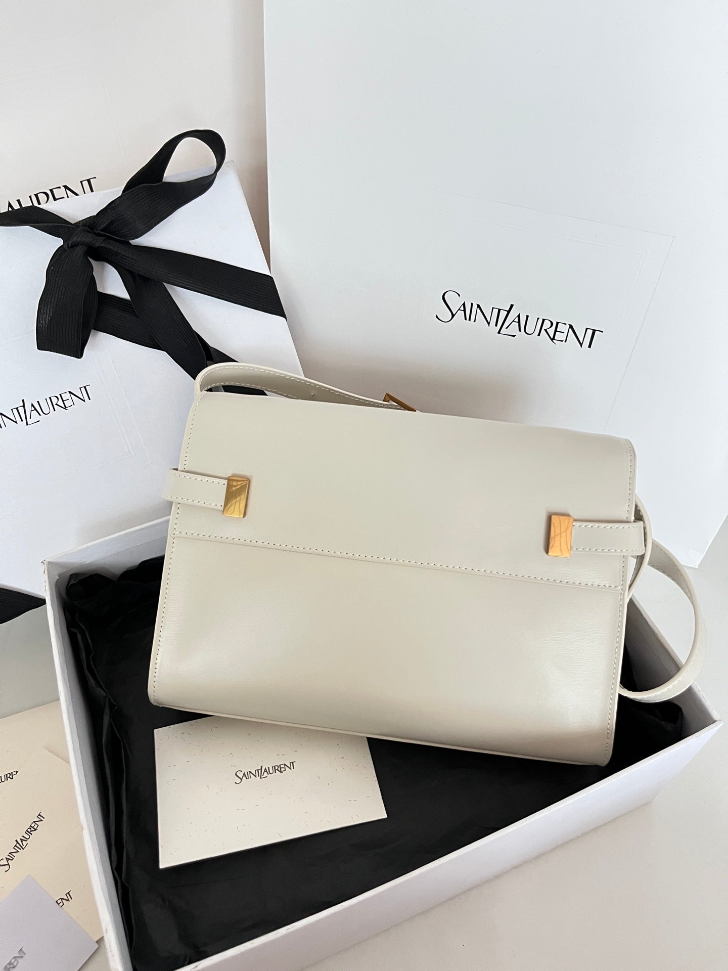Cream leather handbag with gold clasp and curved shoulder strap, front view