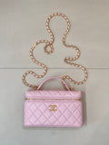 Pink quilted handbag with top handle, gold logo charm, and long jeweled chain strap