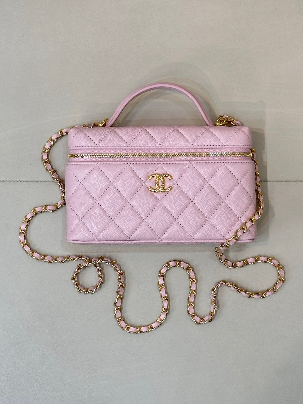 Pink quilted Chanel-style handbag with top handle, zipper top, and jeweled chain strap