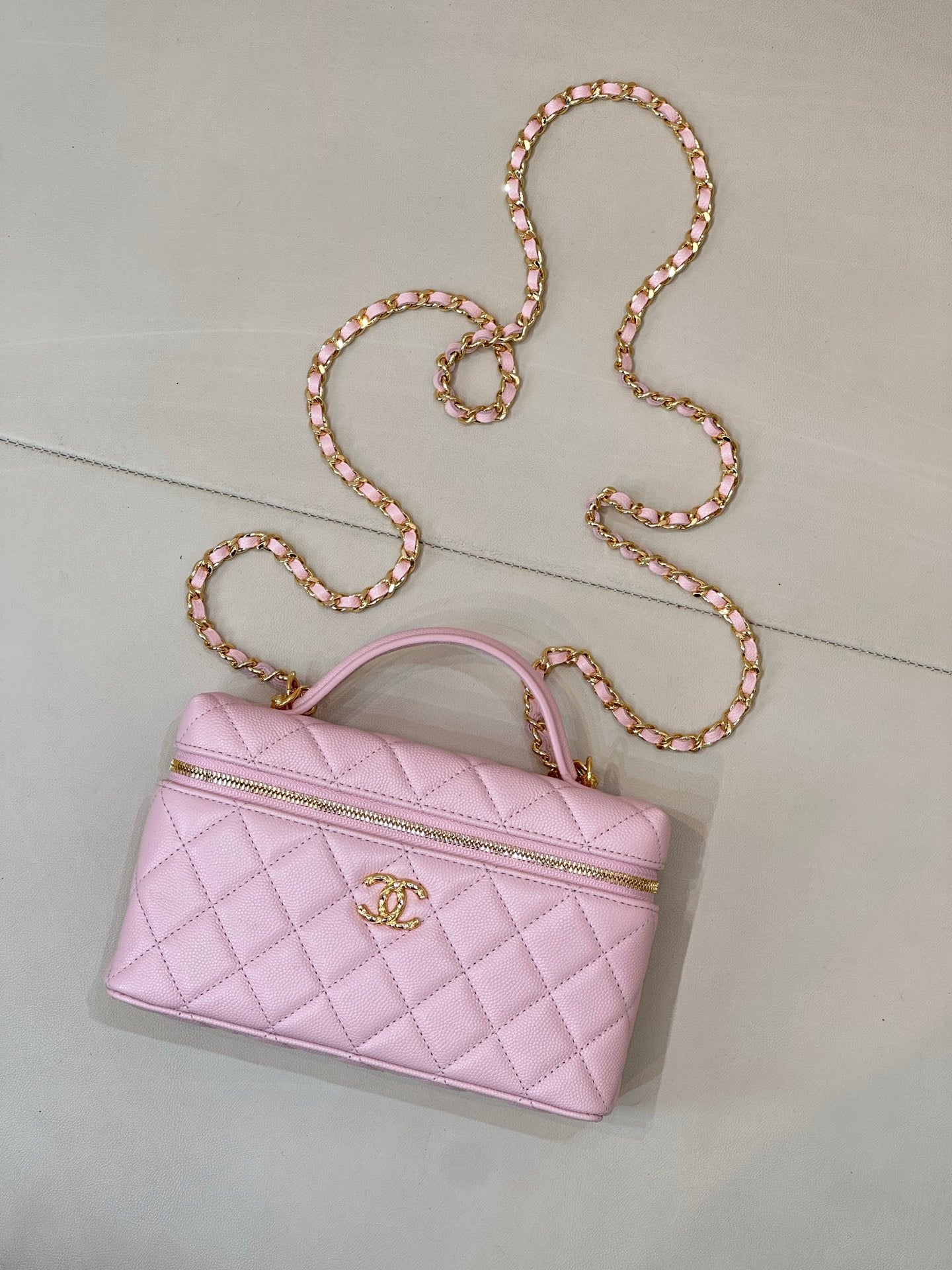 Pink quilted shoulder bag with top handle, gold logo charm, and jeweled chain strap