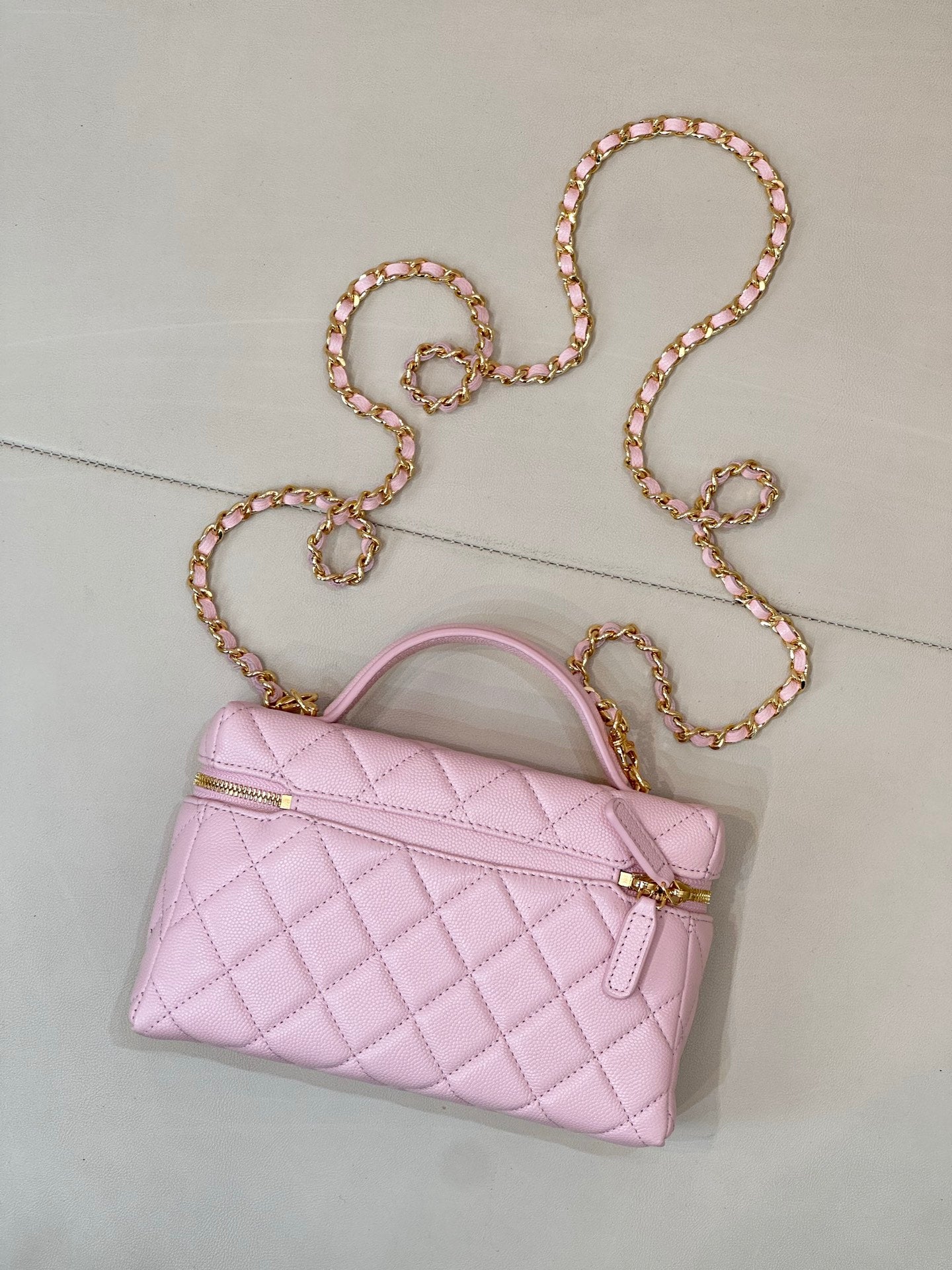 Pink quilted mini shoulder bag with gold zipper, logo charm, and jeweled chain strap