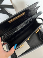 Black crocodile-embossed handbag interior view with gold bar hardware and strap