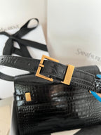 Black crocodile-embossed handbag with gold buckle on front strap