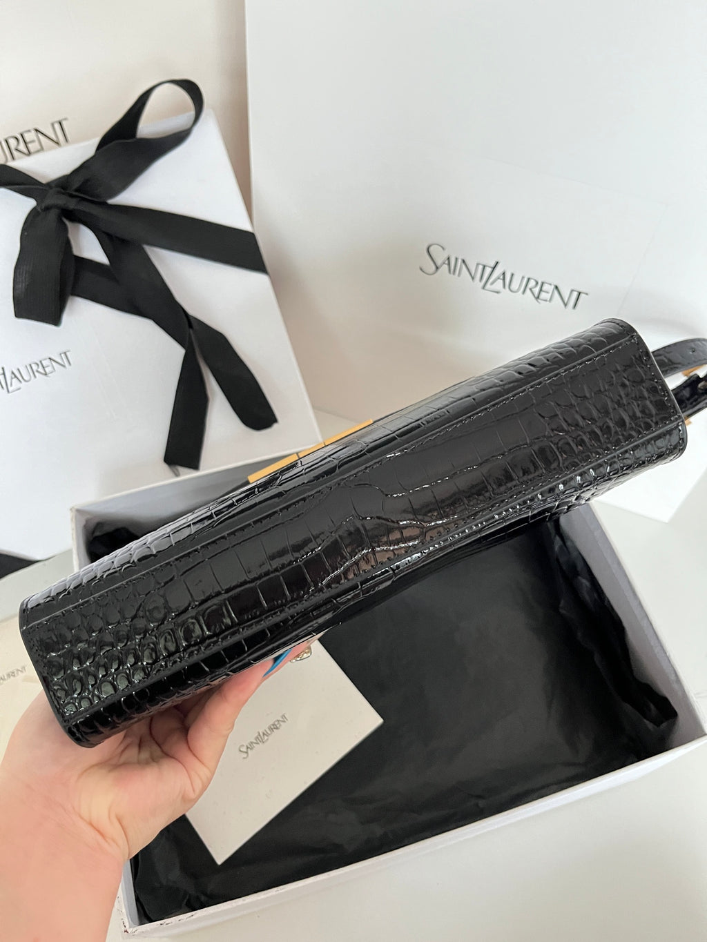 Crocodile-embossed handbag in black with gold-trim hardware, side profile