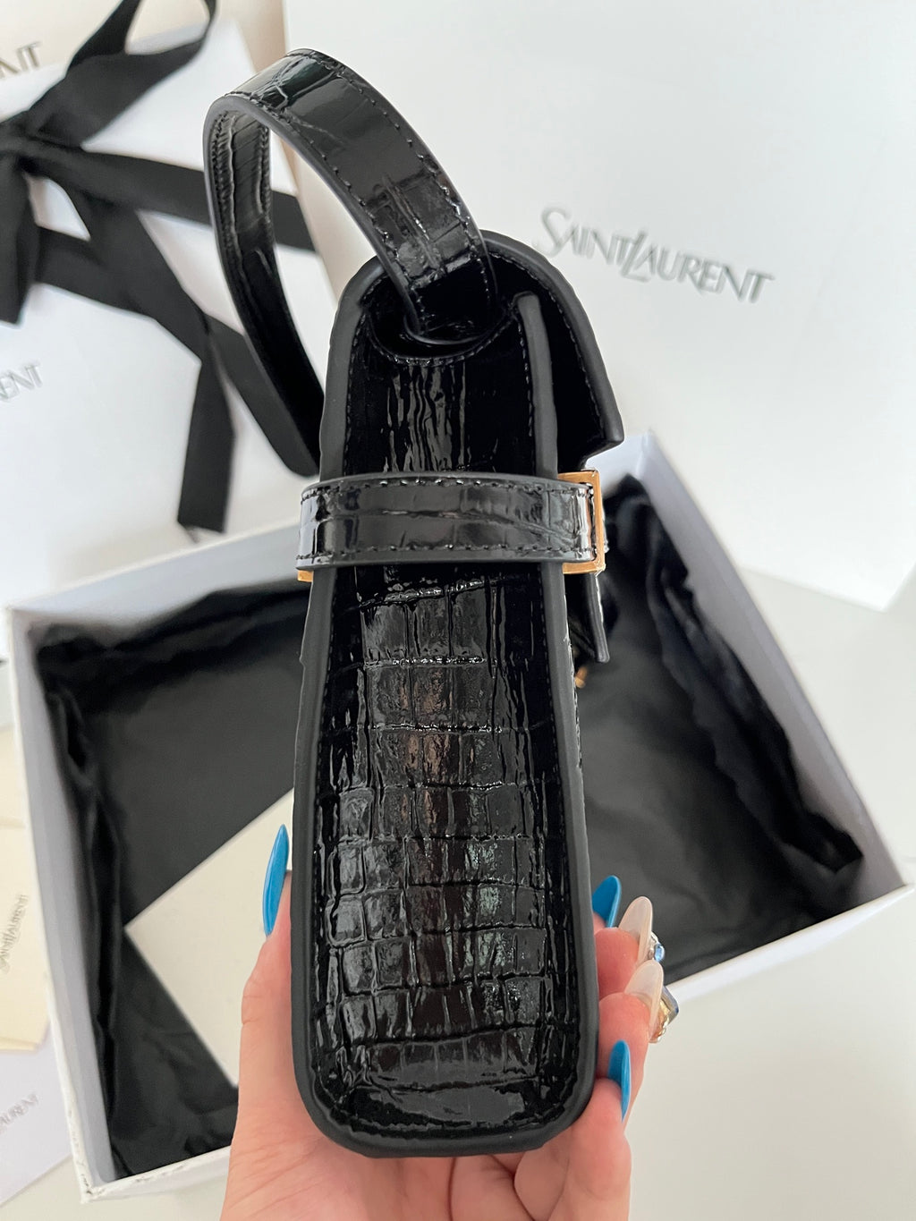 Black crocodile-embossed mini bag with curved top handle and gold strap buckle
