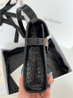 Black crocodile-embossed mini bag with curved top handle and gold strap buckle